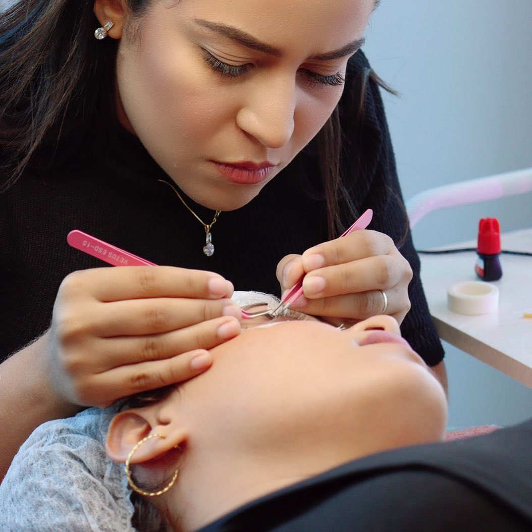 Homem negro com moletom bege mexendo no celular e sorrindo